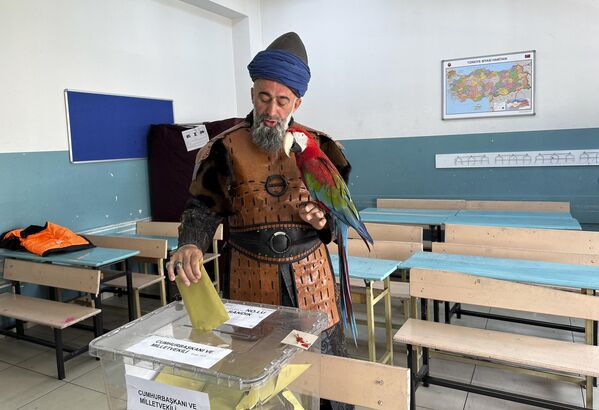 ناظم جهان، 48 ساله،با  پرنده خود  در یکی از شعبه های رای گیری در استانبول رای می دهد - اسپوتنیک ایران  