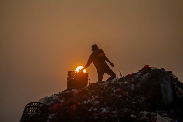 مردی در 25 مه 2023 پس از اتمام تخلیه کامیون های زباله در محل دفن زباله گالوگا در بوگور در 25 مه 2023، اشیایی را جمع آوری می کند که می توانند دوباره بفروشند. (عکس توسط ADITYA AJI / AFP) - اسپوتنیک ایران  