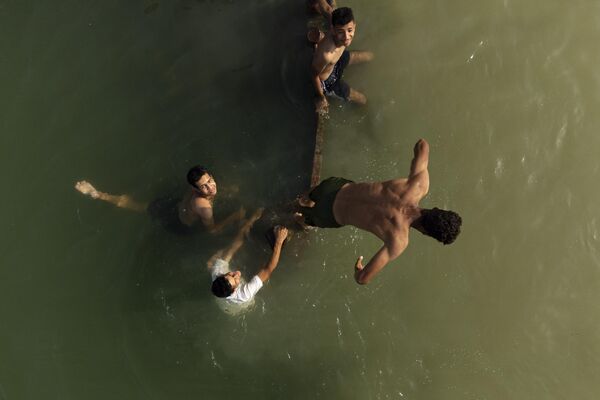 یک تصویر هوایی جوانان را در حال شنا در آبراه شط العرب نشان می دهد که در محل تلاقی رودهای فرات و دجله در شهر جنوبی بصره عراق در 23 مه 2023 تشکیل شده است. (عکس از حسین فلاح / خبرگزاری فرانسه) - اسپوتنیک ایران  