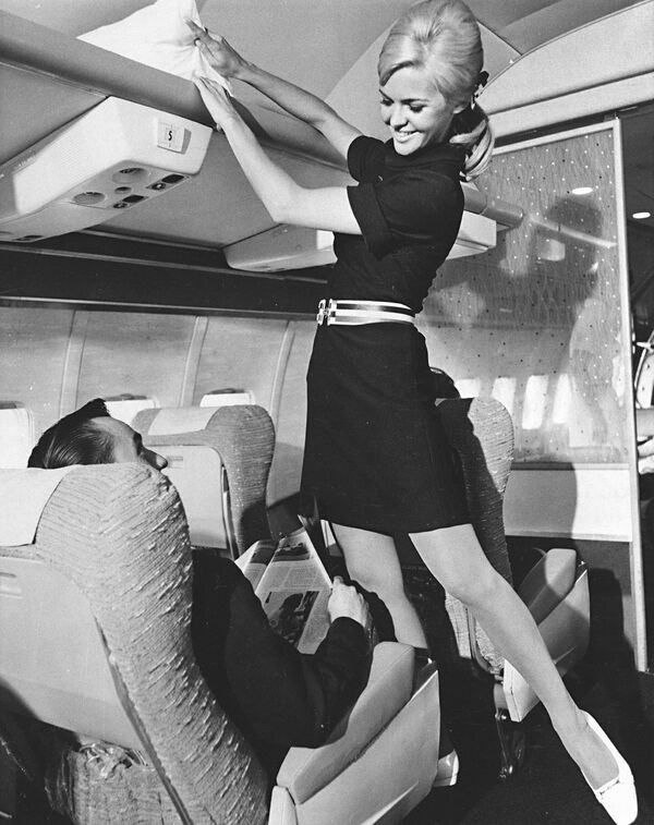 پتی پولسن، مهماندار خطوط هوایی آمریکا، یونیفرم جدید را مدل می‌کند، یک لباس کشدار بافتنی آبی با کمربند و کمان موی مناسب که جایگزین یونیفرم سنتی سه تکه خواهد شد، در سال 1967. زانو (عکس AP) - اسپوتنیک ایران  