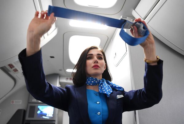 یک مهماندار هواپیما قوانین استفاده از کمربند ایمنی را در کابین هواپیمایی Pobeda در فرودگاه Vnukovo به نام A. N. Tupolev نشان می دهد. - اسپوتنیک ایران  