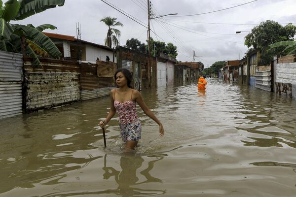 زنی در حال عبور از خیابانی پر آب پس از باران های سیل آسا در شهر والنسیا، ایالت کارابوبو، ونزوئلا - اسپوتنیک ایران  