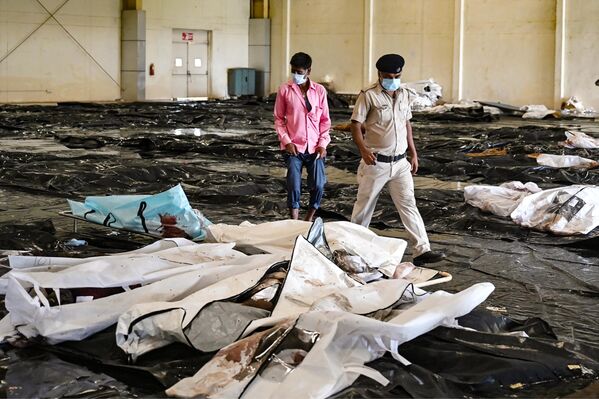 یک پلیس به مردی کمک میکند تا جسد یکی از اعضای خانوادهاش را در یک پارک تجاری که بهعنوان سردخانه موقت مردگان بازیابی شده از لاشه واگن تصادف سه قطار در نزدیکی بالاسوره، در ایالت اودیشا در شرق هند، استفاده میشود، شناسایی کند. یک پلیس به مردی کمک میکند تا جسد یکی از اعضای خانوادهاش را در یک پارک تجاری که بهعنوان سردخانه موقت مردگان بازیابی شده از لاشه واگن تصادف سه قطار در نزدیکی بالاسوره، در ایالت اودیشا در شرق هند، استفاده میشود، شناسایی کند. - اسپوتنیک ایران