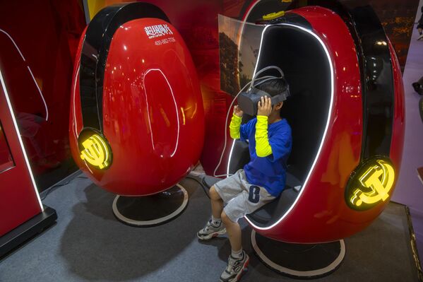 پسری با کمک هدست در نمایشگاه «پی تی اکسپو» در پکن در یک تور واقعیت مجازی "پرچم قرمز" شرکت می کند. - اسپوتنیک ایران  