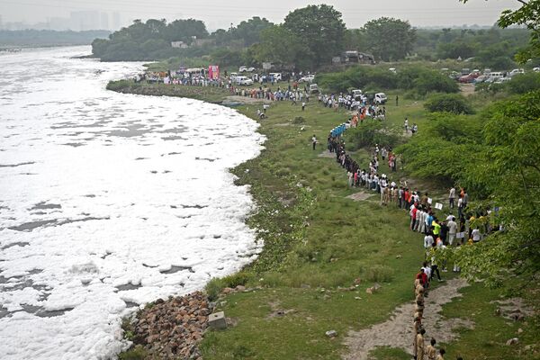 مردم در آستانه روز جهانی محیط زیست در دهلی نو در 4 ژوئن 2023، زنجیره ای انسانی برای پاکسازی آب های آلوده رودخانه یامونا مملو از کف تشکیل دادند. - اسپوتنیک ایران  