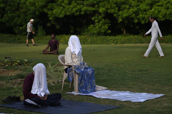 مردم در حالی که صورت خود را پوشانده اند  در پارکی در دهلی نو مدیتیشن می کنند. چهارشنبه 14 ژوئن 2023. - اسپوتنیک ایران  