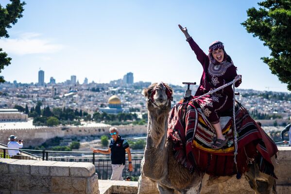 یک گردشگر  سوار بر شتر  بر روی کوه زیتون مشرف بر شهر قدیمی اورشلیم.  12 ژوئن 2023. - اسپوتنیک ایران  