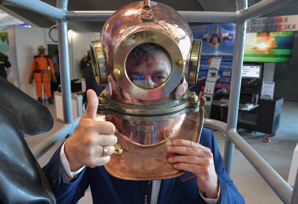 یک بازدیدکننده در غرفه خدمات غواصی در نمایشگاه بین المللی نیروی دریایی IMDS-2023 در شهر کرونشتات روسیه، کلاه ایمنی را امتحان می کند - اسپوتنیک ایران  