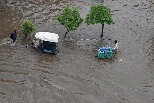 مردم پس از بارندگی شدید در لاهور در 26 ژوئن 2023 در حال عبور از یک مسیر پرآب - اسپوتنیک ایران  