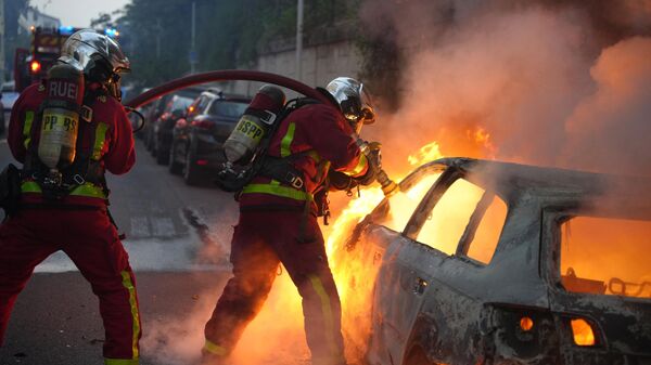 مامور آتش نشانی یک ماشین در حال سوختن را در شهر نانتر در غرب پاریس خاموش می کند - اسپوتنیک ایران  