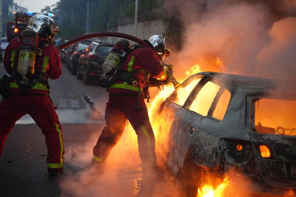 یک آتش نشان یک ماشین در حال سوختن را در شهر نانتر، واقع در غرب پاریس خاموش می کند - اسپوتنیک ایران  