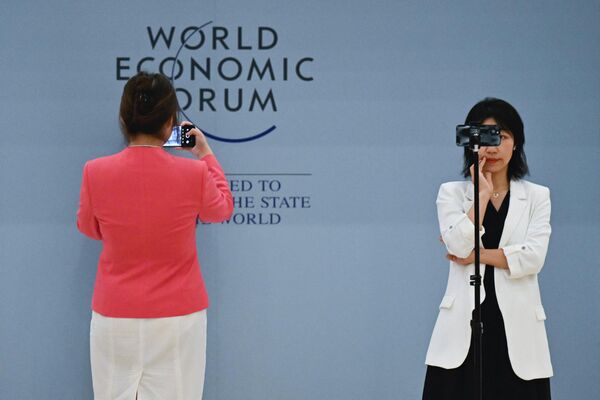 یک شرکت کننده و یک خبرنگار از تلفن های همراه  خود در مرکز همایش و نمایشگاه میجیانگ در طول نشست سالانه قهرمانان جدید مجمع جهانی اقتصاد در تیانجین در 28 ژوئن 2023 استفاده می کنند. - اسپوتنیک ایران  
