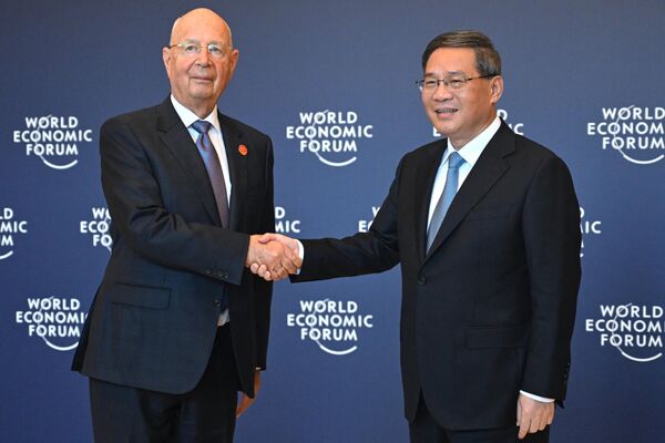  نخست‌وزیر چین، لی کیانگ (سمت راست) با کلاوس شواب، بنیانگذار و رئیس هیئت مدیره مجمع جهانی اقتصاد، قبل از نشست دوجانبه آنها در تیانجین در 26 ژوئن 2023، پیش از نشست سالانه قهرمانان جدید مجمع جهانی اقتصاد (WEF) دست می‌دهد. - اسپوتنیک ایران  