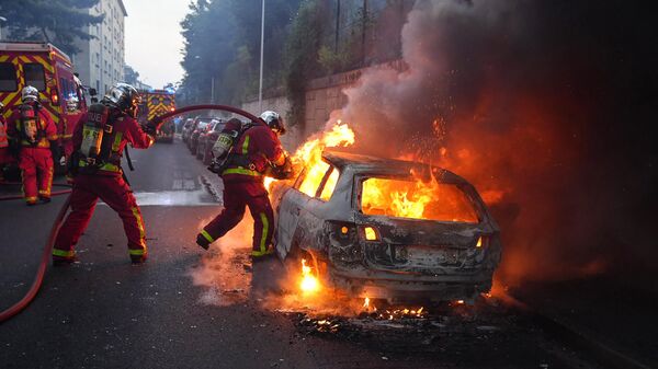 Пожарные тушат горящий автомобиль на обочине демонстрации в Нантере, Франция - اسپوتنیک ایران  