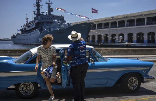 یک زن گردشگر از یک ماشین کلاسیک آمریکایی در مقابل ناو آموزشی نیروی دریایی روسیه &quot;پرکوپ&quot; در خلیج هاوانا، کوبا پیاده می شود - اسپوتنیک ایران  