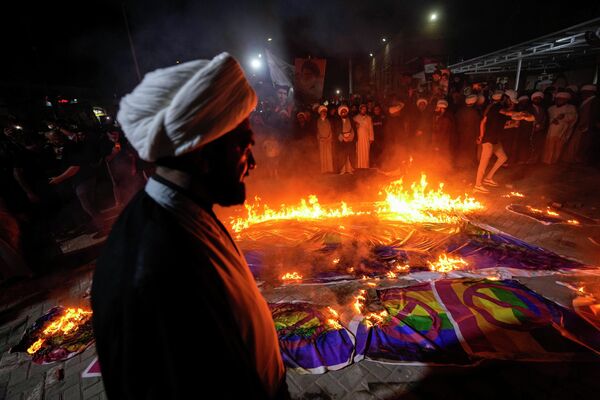 حامیان مقتدی صدر، رهبر مسلمانان شیعه، پرچم های رنگین کمان را در جریان تظاهراتی در شهرک صدر در واکنش به آتش زدن قرآن در سوئد، به آتش کشیدند. بغداد، عراق، چهارشنبه 12 ژوئیه 2023 (AP Photo/Hadi Mizban) - اسپوتنیک ایران  