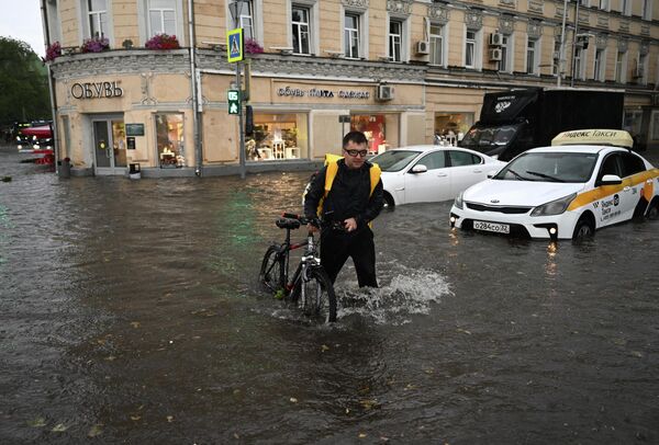 مردی با دوچرخه در خیابانی سیل زده در اثر بارش باران در مسکو - اسپوتنیک ایران  