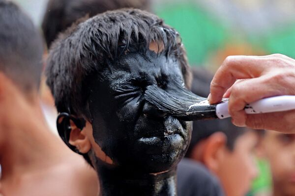  صورت پسر بچه‌ای برای تدارک اجرای مراسم سالانه تعزیه سیاه شده است. شهر نوش آباد، ایران، 26 جولای 2023. - اسپوتنیک ایران  