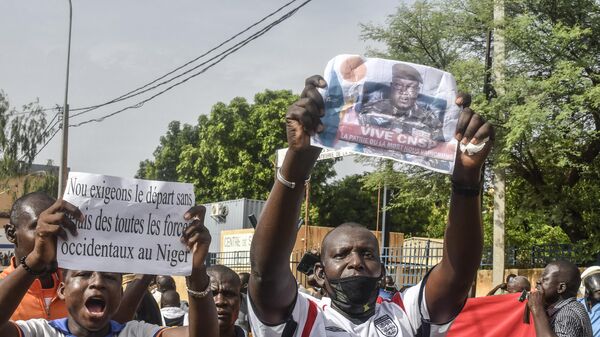 Один из сторонников держит в руках фотографию нигерского генерала Абдурахамана Тиани, начальника могущественной президентской гвардии, когда другие митингуют в поддержку нигерийской хунты в Ниамее - اسپوتنیک ایران  