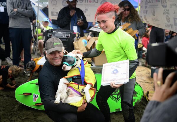  سگی به نام «فی یت» و صاحبان مایک وال و جیمز وال  پس از برنده شدن در دسته سگ های بزرگ مسابقات جهانی موج سواری سگ در پاسیفیکا، کالیفرنیا. - اسپوتنیک ایران  