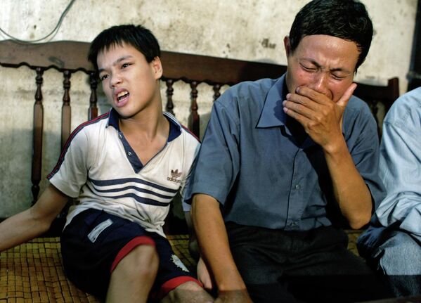 نگوین ون کوی، 49 ساله، در حالی که با پسرش نگوین کوانگ ترنگ، 17 ساله، در خانه اش در های فونگ، ویتنام در ژوئیه 2004 نشسته بود، گریه می کرد. کوی معتقد است که نقص مادرزادی فرزندانش توسط عامل نارنجی ایجاد شده است که او در طول جنگ ویتنام در معرض آن قرار گرفته است. - اسپوتنیک ایران  