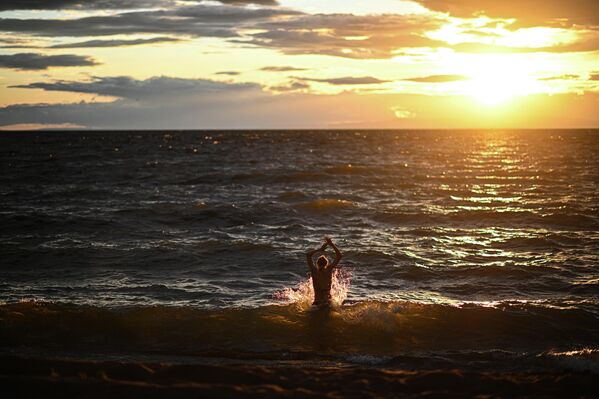شنا در آبهای طلایی بایکال هنگام غروب در روستای تورکا در بوریاتیا واقع در حاشیه بایکال. - اسپوتنیک ایران  