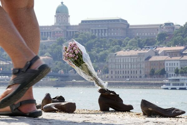 مردم در  مجسمه های یادبود کفش‌های یهودیان در امتداد ساحل دانوب، به یاد یهودیان بوداپست که در سال 1944 توسط ارتش مجارستانی راست افراطی  به آنها در رودخانه  تیراندازی شد، گل‌ گذاشتند. - اسپوتنیک ایران  