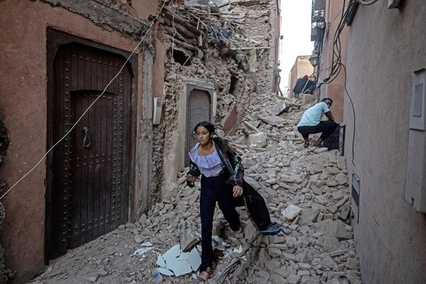 یک زن با وسایل خود در حال خارج شدن  از زیر آوار در شهر قدیمی مراکش آسیب دیده از زلزله در 9 سپتامبر 2023 می باشد. مقامات در 9 سپتامبر گفتند که مرگبارترین زمین لرزه مراکش در دهه های اخیر دست کم 1000 کشته برجای گذاشته است و خسارات گسترده ای به بار آورده و ساکنان و گردشگران وحشت زده را در نیمه های شب به مکان امن فرستاده است.(Photo by FADEL SENNA / AFP) - اسپوتنیک ایران  