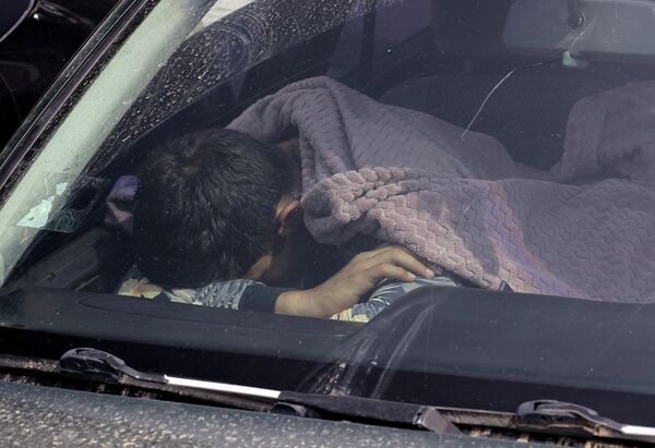 یک پناهجو در ماشینی در نزدیکی یک مرکز بشردوستانه در شهر گوریس خوابیده است. - اسپوتنیک ایران  