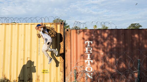 Мигрант из Венесуэлы перепрыгивает заграждения из колючей проволоки на мексико-американской границе в Игл-Пасс, штат Техас - اسپوتنیک ایران  