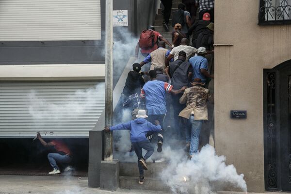 حامیان اپوزیسیون در ماداگاسکار در حالی که افسران پلیس ضدشورش از گاز اشک آور برای متفرق کردن آنها در آنتاناناریوو در 2 اکتبر 2023 استفاده می کنند - اسپوتنیک ایران  