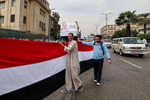حامیان عبدالفتاح السیسی، رئیس جمهور مصر، با پرچم های ملی و سردادن شعارهایی در یک گردهمایی تبلیغاتی انتخاباتی در خارج از محوطه دانشگاه قاهره در شهر جیزه، شهر دوقلوی پایتخت مصر، در 2 اکتبر 2023 تجمع کردند. - اسپوتنیک ایران  