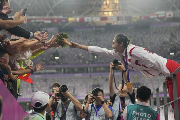 لی لینگ، دارنده مدال طلا از چین، دسته گل خود را به هواداران در مراسم پیروزی برای پرش با میله زنان هدیه می دهد. 2 اکتبر 2023 - اسپوتنیک ایران  