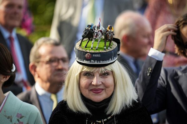 مهمانی که کلاه بر سر دارد، در جریان مسابقه اسب‌سواری قطر Prix de l'Arc de Triomphe، در پاریس، در تاریخ 1 اکتبر 2023 به کورس مسابقه پاریس لانگ‌چمپ می‌رسد. (عکس از Dimitar DILKOFF / AFP) - اسپوتنیک ایران  