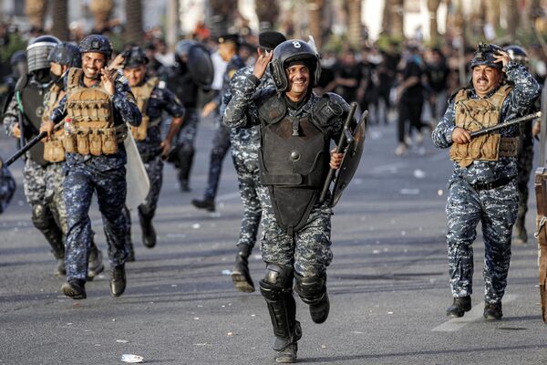 پلیس کنترل شورش معترضانی را که در روز 1 اکتبر 2023 در چهارمین سالگرد تظاهرات ضد دولتی عراق در سال 2019 در میدان تحریر بغداد تجمع کرده بودند، متفرق می کنند - اسپوتنیک ایران  