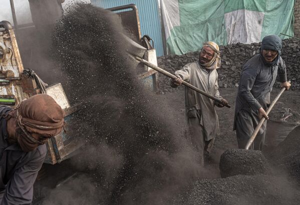 کارگران افغان در 3 اکتبر 2023 زغال سنگ را روی یک کامیون در محوطه زغال سنگ در حومه کابل بیل می کنند - اسپوتنیک ایران  