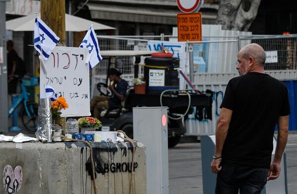 مردی در خیابان نزدیک بازار کارمل در تل آویو یه یادبود موقت به یاد کشته شدگان پس از حمله حماس خیره شده است. - اسپوتنیک ایران  