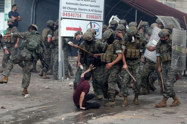 نیروهای امنیتی لبنان هنگام درگیری با معترضان در مقابل سفارت آمریکا در عوکار در شرق بیروت، در جریان تظاهرات همبستگی با فلسطینیان نوار غزه، در 18 اکتبر 2023، یک جوان را با باتوم تهدید کردند. هزاران نفر در سراسر عرب و مسلمان تظاهرات کردند. جهان در 18 اکتبر در اعتراض به کشته شدن صدها نفر در اعتصاب به بیمارستانی در غزه که اسرائیل را علیرغم انکار آن مقصر می دانند. (عکس از ابراهیم امرو / خبرگزاری فرانسه) - اسپوتنیک ایران  