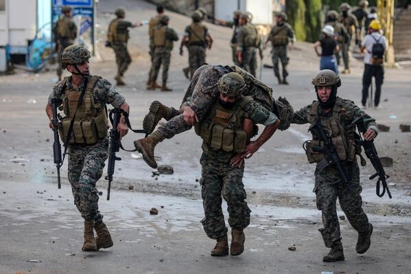 نیروهای امنیتی لبنان یک سرباز دیگر را که در درگیری با معترضان خارج از سفارت آمریکا در عوکار در شرق بیروت در جریان تظاهرات همبستگی با فلسطینیان نوار غزه در 18 اکتبر 2023 مجروح شده بود، با خود بردند. هزاران نفر در سراسر عرب و مسلمان تظاهرات کردند. جهان در 18 اکتبر در اعتراض به کشته شدن صدها نفر در اعتصاب به بیمارستانی در غزه که اسرائیل را علیرغم انکار آن مقصر می دانند. (عکس از ابراهیم امرو / خبرگزاری فرانسه) - اسپوتنیک ایران  