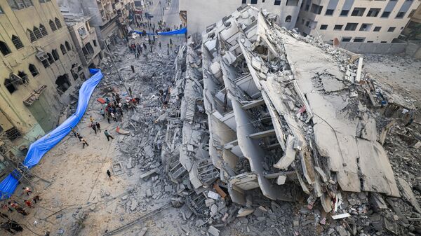 Люди осматривают руины здания, разрушенного в результате израильских ударов в городе Газа - اسپوتنیک ایران  