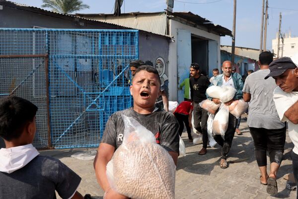 یک پسر فلسطینی کیسه‌ای نخود جمع‌آوری شده از یک مرکز کمک‌رسانی سازمان ملل را در دست دارد و غذا را بین فلسطینی‌های محلی و مردم آواره‌شده توزیع می‌کند.  - اسپوتنیک ایران  