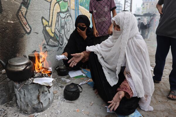 زنان در رفح در جنوب نوار غزه کاغذ می سوزانند تا آب را برای چای گرم کنند.  - اسپوتنیک ایران  
