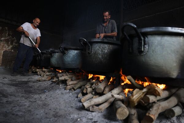 مردان فلسطینی به دلیل کمبود گاز برای پخت و پز، غذا را در دیگ های بزرگی که روی آتش های چوبی می جوشند، آماده می کنند. - اسپوتنیک ایران  