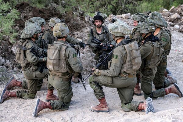 سربازان ارتش اسرائیل در 1 نوامبر 2023 در میان افزایش تنش‌های فرامرزی بین حزب‌الله و اسرائیل در حالی که درگیری‌ها در جنوب با شبه‌نظامیان حماس در نوار غزه ادامه دارد، زانو زده و در موقعیتی در منطقه الجلیل بالا در شمال اسرائیل در نزدیکی مرز با لبنان نشسته‌اند. - اسپوتنیک ایران  