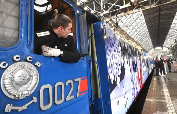 راننده قطار قبل از حرکت &quot;قطار بابانوئل&quot; از مسکو. این پروژه مشترک راه آهن روسیه و دولت منطقه وولوگدا است که در چارچوب آن بابانوئل با یک برنامه جشن سال نو به شهرهای روسیه سفر می کند و برای کسانی که خودشان نمی توانند برای دیدن بابانوئل به اوستیوگ کبیر بروند و قدم به دنیای افسانه ای کریسمس بگذارند، برنامه ای به یادماندنی برایشان برگزار می کند. این پروژه برای اولین بار در 5 دسامبر 2021 آغاز شد. در طی دو سال، بیش از 900 هزار نفر در بیش از 150 شهر روسیه در آن شرکت کردند. - اسپوتنیک ایران  