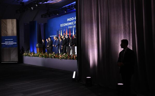 یک مامور سرویس مخفی از کنار صحنه تماشا می‌کند که جو بایدن، رئیس‌جمهور ایالات متحده با رهبران سازمان همکاری اقتصادی آسیا-اقیانوسیه (APEC) در سانفرانسیسکو عکسی دسته جمعی می گیرد. 16 نوامبر 2023. - اسپوتنیک ایران  