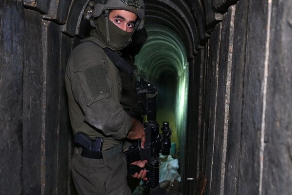 --عکس گرفته شده در طی یک تور کنترل شده و متعاقباً ویرایش شده تحت نظارت ارتش اسرائیل-- یک سرباز در تونلی ایستاده است که ارتش اسرائیل می گوید توسط شبه نظامیان حماس در داخل مجتمع بیمارستان الشفا در شمال شهر غزه در غزه حفر شده است. نوار، در میان ادامه نبردهای بین اسرائیل و گروه شبه نظامی فلسطینی حماس، در 22 نوامبر 2023. (عکس از Ahikam SERI / AFP) - اسپوتنیک ایران  