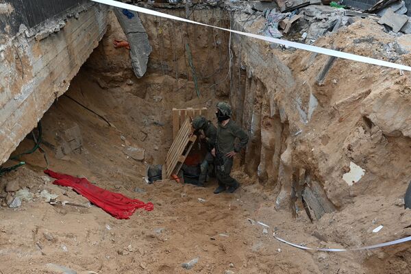 --عکس گرفته شده در طی یک تور کنترل شده و متعاقباً ویرایش شده تحت نظارت ارتش اسرائیل-- سربازان در کنار آنچه ارتش اسرائیل می گوید ورودی تونلی است که توسط شبه نظامیان حماس در داخل شهر الشفا در مجتمع بیمارستانی در غزه حفر شده است ایستاده اند. شمال نوار غزه، در بحبوحه نبردهای ادامه دار بین اسرائیل و گروه شبه نظامی فلسطینی حماس، در 22 نوامبر 2023. (عکس از Ahikam SERI / AFP) - اسپوتنیک ایران  