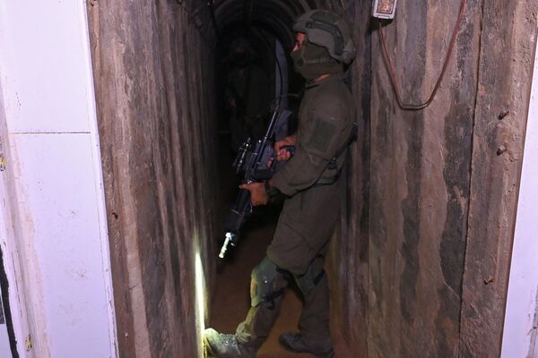 --عکس گرفته شده در طی یک تور کنترل شده و متعاقباً ویرایش شده تحت نظارت ارتش اسرائیل-- یک سرباز در تونلی ایستاده است که ارتش اسرائیل می گوید توسط شبه نظامیان حماس در داخل مجتمع بیمارستان الشفا در شمال شهر غزه در غزه حفر شده است. نوار، در میان ادامه نبردهای بین اسرائیل و گروه شبه نظامی فلسطینی حماس، در 22 نوامبر 2023. (عکس از Ahikam SERI / AFP) - اسپوتنیک ایران  