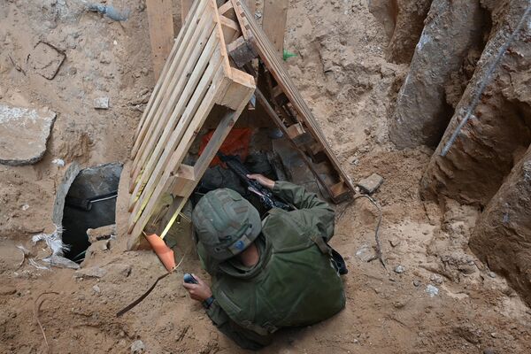 --عکس گرفته شده در طی یک تور کنترل شده و متعاقباً ویرایش شده تحت نظارت ارتش اسرائیل-- یک سرباز به داخل آنچه ارتش اسرائیل می گوید ورودی تونلی است که توسط شبه نظامیان حماس در داخل شهر الشفا در مجتمع بیمارستانی در غزه حفر شده است بالا می رود. شمال نوار غزه، در بحبوحه نبردهای ادامه دار بین اسرائیل و گروه شبه نظامی فلسطینی حماس، در 22 نوامبر 2023. (عکس از Ahikam SERI / AFP) - اسپوتنیک ایران  